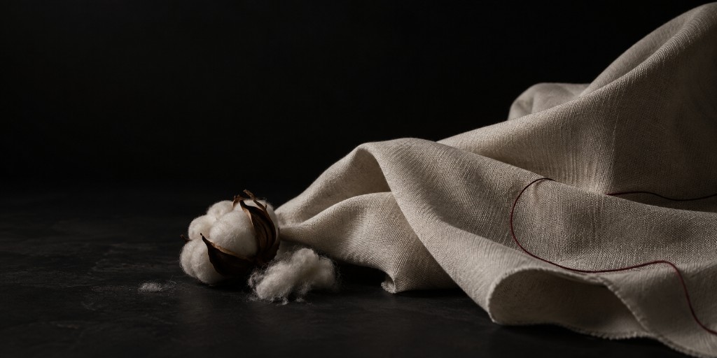 Raw cotton boll beside draped undyed cloth